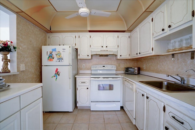 kitchen featuring white appliances, white cabinets, vaulted ceiling, and sink