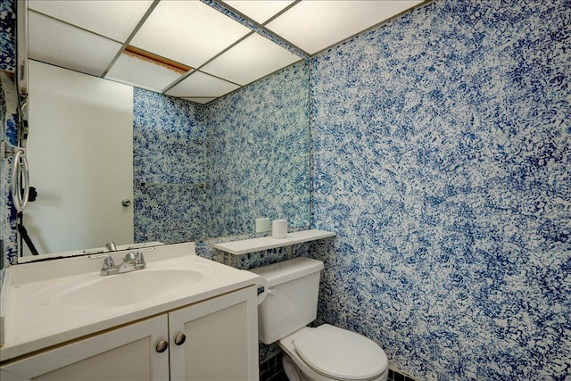 bathroom featuring a drop ceiling, vanity, and toilet