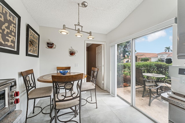 dining room with lofted ceiling, light tile patterned floors, and a textured ceiling