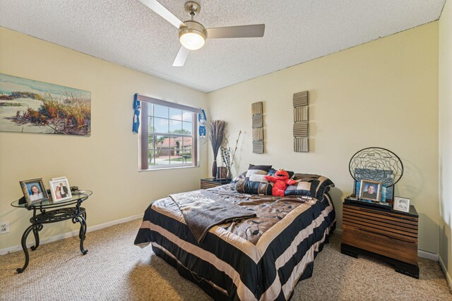 bedroom with ceiling fan, light colored carpet, and a textured ceiling