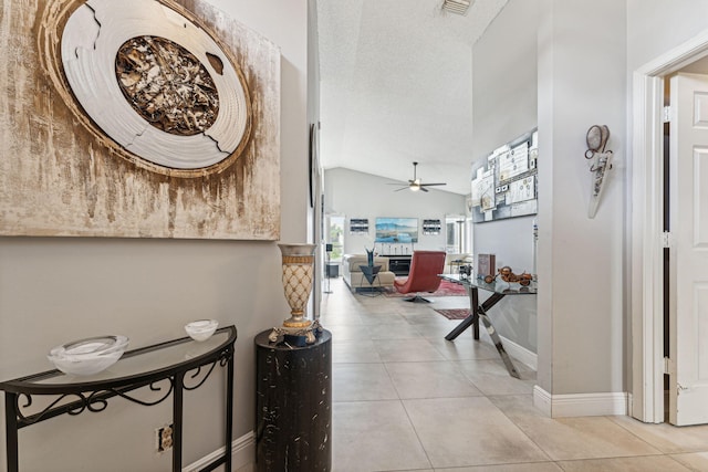 hall featuring light tile patterned flooring, lofted ceiling, and a textured ceiling