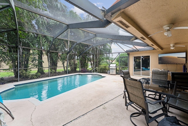 view of pool with ceiling fan, area for grilling, glass enclosure, and a patio area