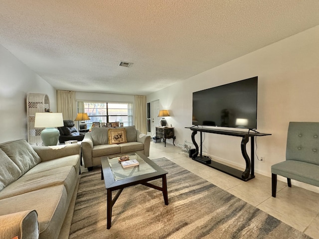 tiled living area featuring baseboards, a textured ceiling, and visible vents
