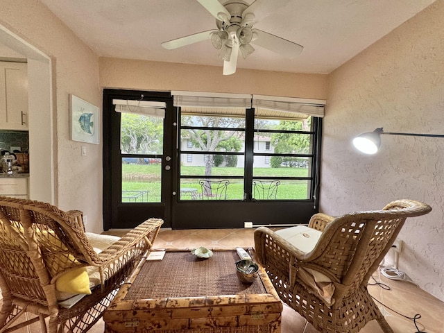 living area featuring a textured wall, ceiling fan, and tile patterned floors