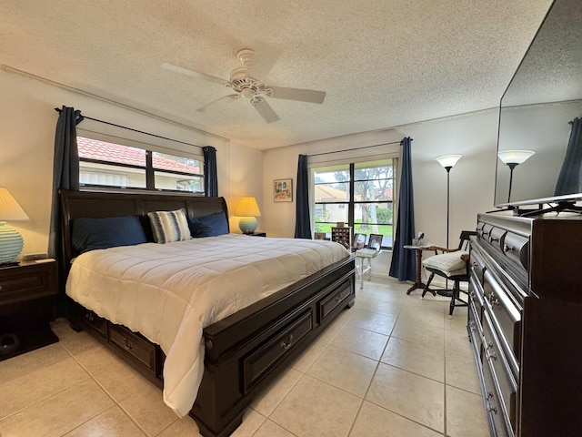 bedroom with ceiling fan, light tile patterned floors, and a textured ceiling