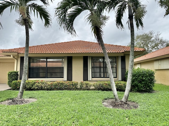 ranch-style house with an attached garage, a front lawn, stucco siding, and a tiled roof