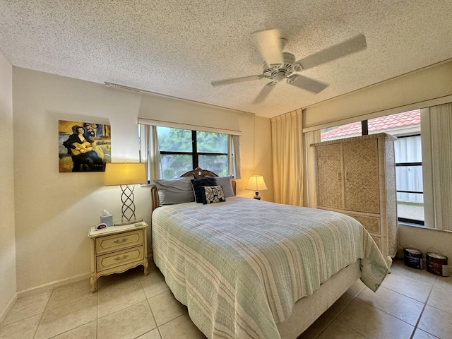 bedroom featuring light tile patterned floors, multiple windows, a ceiling fan, and a textured ceiling