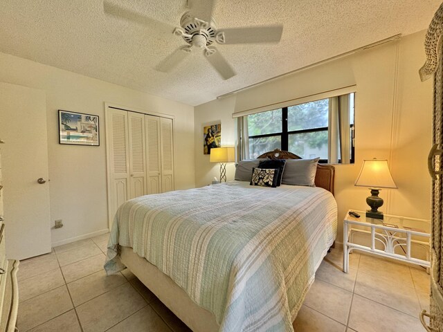 bedroom with a closet, a textured ceiling, ceiling fan, and light tile patterned flooring