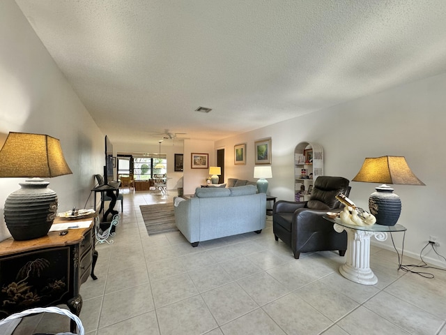 living room featuring light tile patterned flooring, a textured ceiling, and visible vents