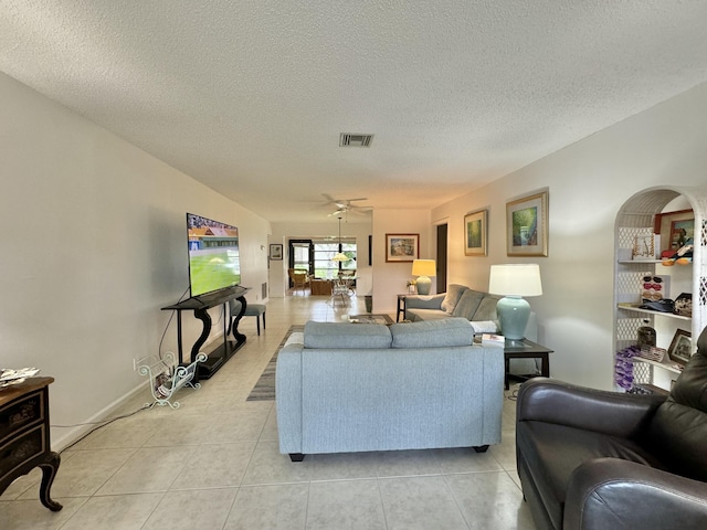 living room with visible vents, a ceiling fan, a textured ceiling, and light tile patterned floors