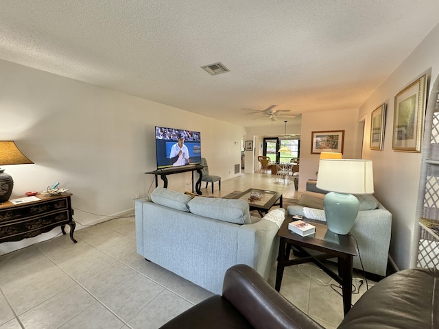 tiled living room with ceiling fan and a textured ceiling