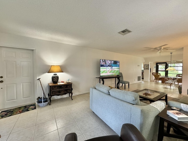 living area featuring a ceiling fan, a textured ceiling, visible vents, and light tile patterned flooring