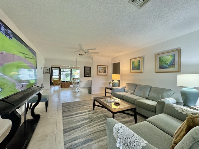 living room with ceiling fan, a textured ceiling, visible vents, baseboards, and light tile patterned flooring
