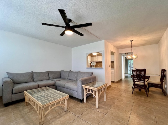 tiled living room with ceiling fan with notable chandelier and a textured ceiling