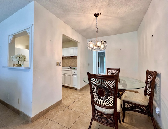 dining space featuring sink, light tile patterned floors, a chandelier, and a textured ceiling