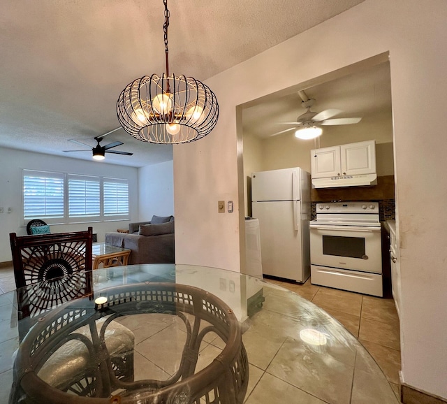 dining room featuring ceiling fan with notable chandelier, light tile patterned floors, and a textured ceiling