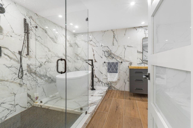 bathroom with tile walls, shower with separate bathtub, vanity, and wood-type flooring