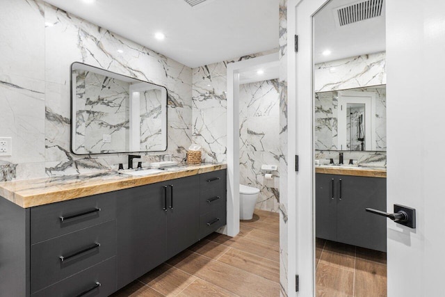 bathroom featuring toilet, tile walls, hardwood / wood-style floors, tasteful backsplash, and vanity