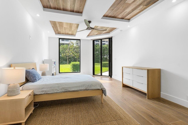 bedroom featuring light hardwood / wood-style floors, access to exterior, wooden ceiling, ceiling fan, and a raised ceiling