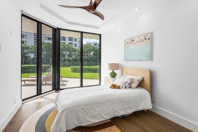 bedroom featuring ceiling fan, multiple windows, a raised ceiling, and access to outside