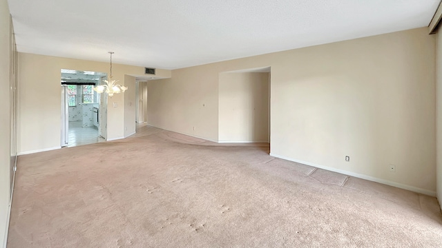 spare room with an inviting chandelier and carpet