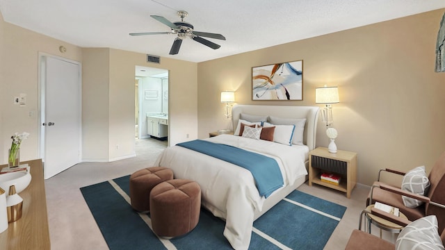 bedroom featuring ceiling fan, ensuite bathroom, light carpet, and a textured ceiling