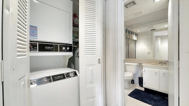 washroom with stacked washer / dryer, tile patterned flooring, and sink