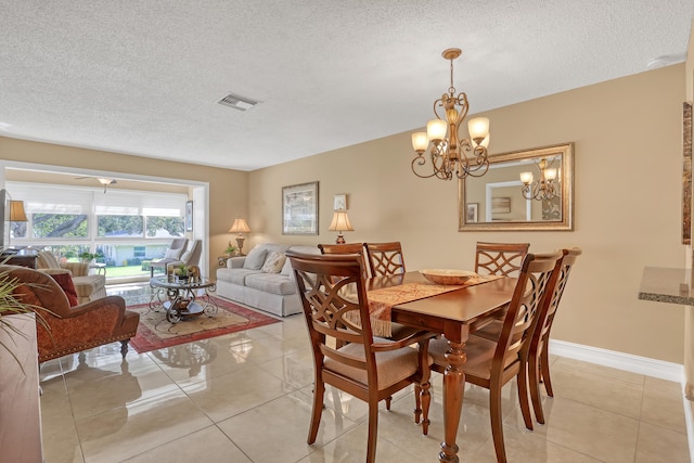 dining space with a textured ceiling, light tile patterned flooring, and an inviting chandelier