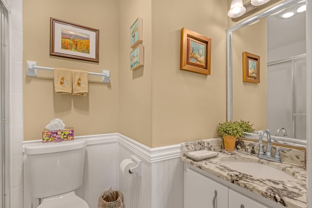 bathroom featuring vanity, a shower with shower door, and toilet