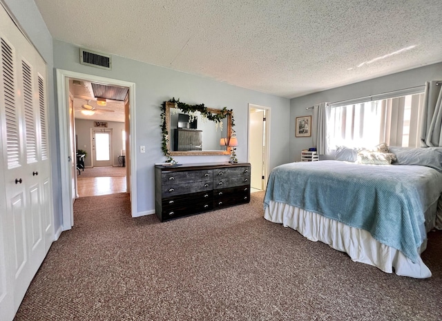 carpeted bedroom featuring multiple windows, a textured ceiling, and a closet