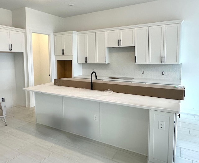 kitchen featuring white cabinetry, sink, a kitchen island with sink, and decorative backsplash