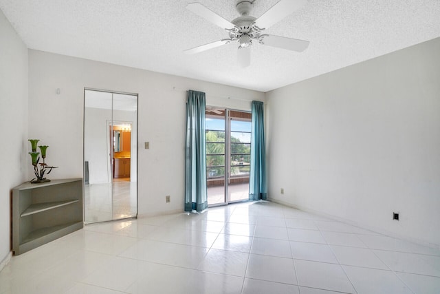 tiled empty room with a textured ceiling and ceiling fan