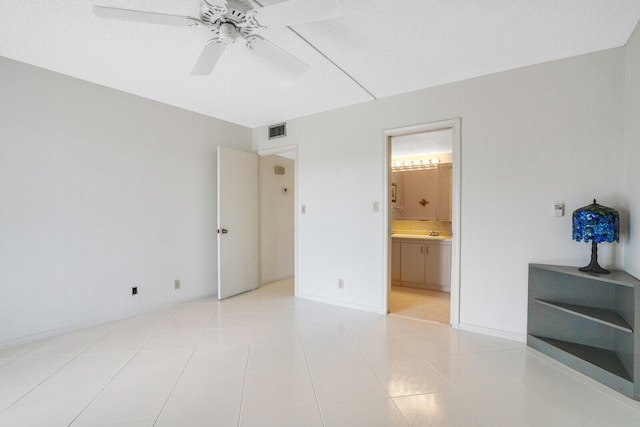 unfurnished bedroom with connected bathroom, ceiling fan, a textured ceiling, and light tile patterned floors