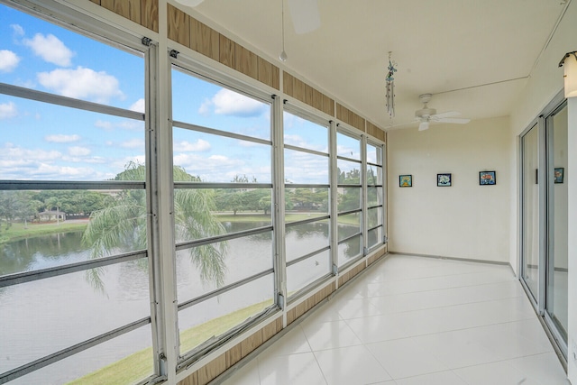 unfurnished sunroom featuring a healthy amount of sunlight, a water view, and ceiling fan