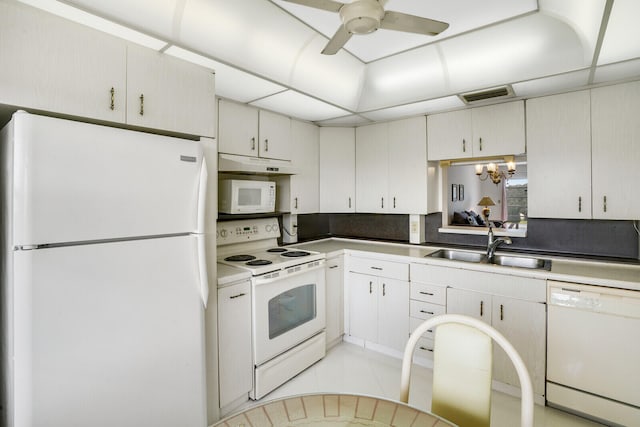 kitchen featuring decorative backsplash, white appliances, sink, light tile patterned floors, and ceiling fan with notable chandelier