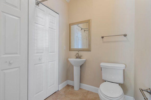 bathroom with toilet, baseboards, tile patterned floors, and a sink