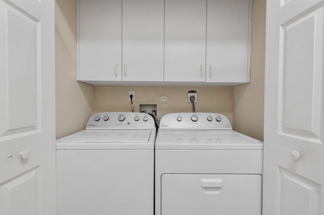 clothes washing area featuring separate washer and dryer and cabinets