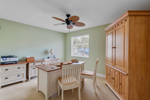 home office featuring light carpet, a textured ceiling, and ceiling fan