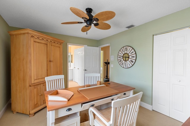 home office featuring light carpet, a textured ceiling, and ceiling fan