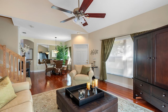 living room with a ceiling fan, wood finished floors, stairway, arched walkways, and baseboards
