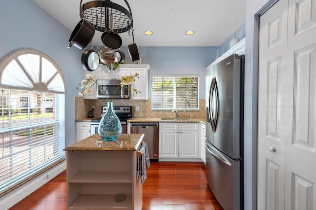 kitchen with stainless steel appliances, a sink, open shelves, decorative backsplash, and white cabinetry