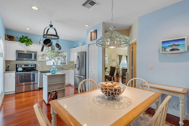 dining space featuring light wood finished floors, a chandelier, recessed lighting, and a textured ceiling