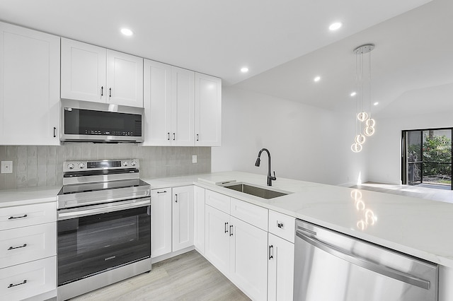 kitchen featuring sink, white cabinetry, decorative light fixtures, kitchen peninsula, and stainless steel appliances