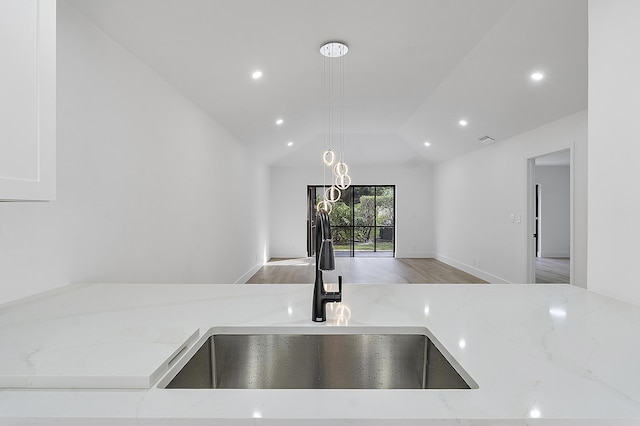 kitchen featuring lofted ceiling, sink, and light stone counters