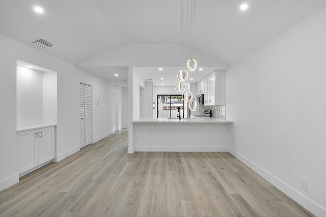 unfurnished living room with lofted ceiling, sink, and light hardwood / wood-style flooring