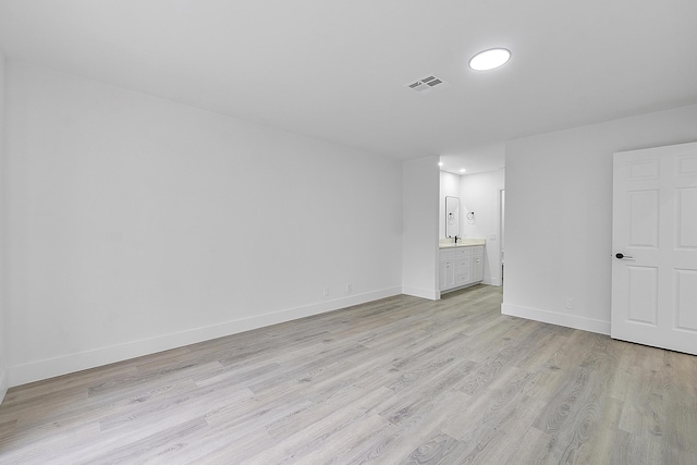 unfurnished bedroom with ensuite bath and light wood-type flooring