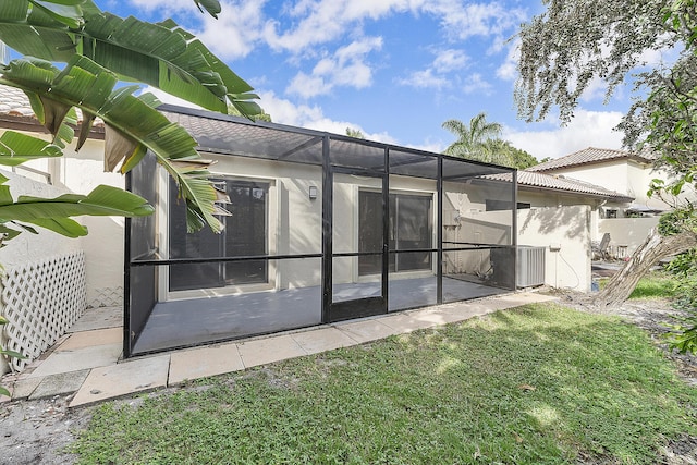 rear view of property featuring a yard and glass enclosure