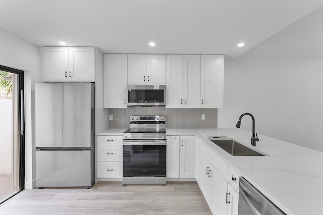 kitchen with white cabinetry, appliances with stainless steel finishes, sink, and backsplash