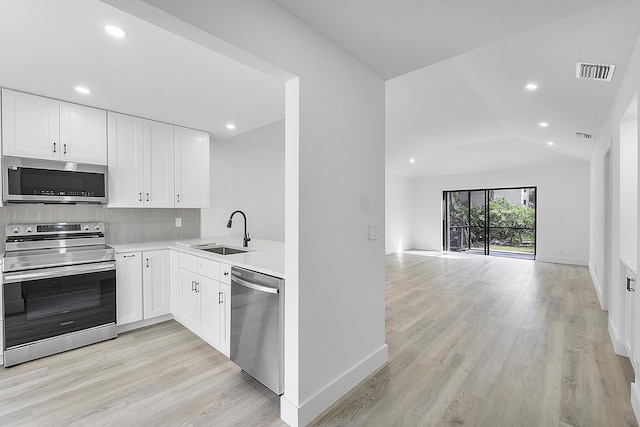 kitchen with sink, vaulted ceiling, stainless steel appliances, and white cabinets