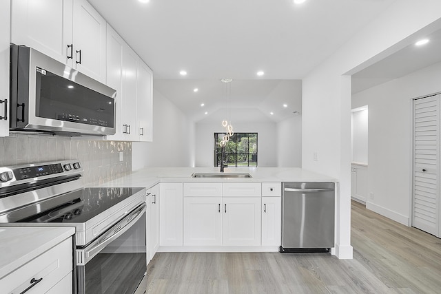 kitchen with sink, white cabinetry, vaulted ceiling, kitchen peninsula, and stainless steel appliances